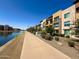 Scenic exterior of modern apartments with a pathway along the canal and a 'For Sale' sign at 4803 N Woodmere Fairway -- # 2006, Scottsdale, AZ 85251