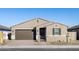 Tan house with brown garage door, black gate, and landscaping at 17738 W Coolidge St, Goodyear, AZ 85395