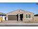 Tan house with brown garage door, black gate, and landscaping at 17738 W Coolidge St, Goodyear, AZ 85395