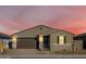 Tan house with brown garage door, black gate, and landscaping at dusk at 17738 W Coolidge St, Goodyear, AZ 85395