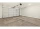 A spacious garage has concrete floors, a large white door, and overhead lighting at 25975 N 160Th Ln, Surprise, AZ 85387