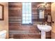 Charming half bathroom with a pedestal sink, rustic wood wall, and glass block window at 15339 E Red Bird Rd, Scottsdale, AZ 85262
