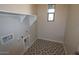 Laundry room with patterned floors, a utility sink, and a window for natural light at 12311 W Parkway Ln, Avondale, AZ 85323