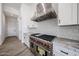 Gourmet kitchen features a stainless steel range hood, Wolf stove, white cabinets, and tile backsplash at 3295 W Mesquite St, Phoenix, AZ 85086