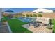 Inviting backyard features a sparkling pool, artificial grass, lounge seating, and a dining area, perfect for relaxation and entertaining at 2228 E Isaiah Ave, Gilbert, AZ 85298