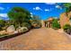Paver driveway leads to a landscaped home with lush greenery and mature trees under a sunny, blue sky at 42383 N 111Th Pl, Scottsdale, AZ 85262