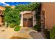 Inviting entrance framed by lush greenery and stone archway, offering a glimpse into the home's charming courtyard at 42383 N 111Th Pl, Scottsdale, AZ 85262
