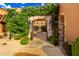 Inviting entrance framed by lush greenery and stone archway, offering a glimpse into the home's charming courtyard at 42383 N 111Th Pl, Scottsdale, AZ 85262
