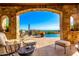 Covered patio with stone archway, outdoor seating, and scenic views of the surrounding landscape at 42383 N 111Th Pl, Scottsdale, AZ 85262