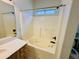 Bathroom featuring a large tub with a shower, white tile surround, and a small window at 9744 N 97Th Ln, Peoria, AZ 85345