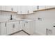 Well-lit laundry room features modern white cabinetry, countertops, and sleek black hardware at 13653 E Aloe Vera Dr, Scottsdale, AZ 85262