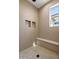 Modern shower with unique tile, bench, window, and built-in shelving at 13653 E Aloe Vera Dr, Scottsdale, AZ 85262