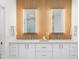 Modern bathroom featuring double sinks, white cabinets, and wood accent wall with illuminated mirrors at 10646 E Butherus Dr, Scottsdale, AZ 85255