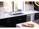 Close-up of a kitchen sink with white countertops, black cabinetry, and modern gold hardware at 10646 E Butherus Dr, Scottsdale, AZ 85255