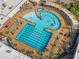 Aerial view of a community pool featuring a distinct design, lounge chairs, and palm trees, and surrounding green spaces at 16001 W Huron Dr, Sun City West, AZ 85375