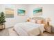 Bedroom with a wicker bed frame, soft pink bedding, and beach-themed art at 30564 N Sydney Dr, San Tan Valley, AZ 85143