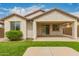 Backyard view of home exterior, covered patio, green grass, and decorative bushes and trees at 10065 E Thatcher Ave, Mesa, AZ 85212