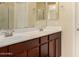 Bathroom featuring a double sink vanity with wood cabinets and a large mirror at 10065 E Thatcher Ave, Mesa, AZ 85212