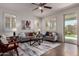 Bright living room with plush sofas, stylish rug, ceiling fan, and sliding glass doors to backyard at 10065 E Thatcher Ave, Mesa, AZ 85212