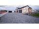 Spacious three-car garage with gray doors, paver driveway, and professionally landscaped yard at 3888 E Weston Ln, San Tan Valley, AZ 85140