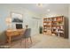 Functional home office with a wooden desk, shelving unit, and neutral decor at 16513 W Windsor Ave, Goodyear, AZ 85395