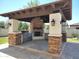 Outdoor kitchen with built-in grill, fireplace, stone accents, and ceiling fan for outdoor gatherings at 18029 W San Miguel Ave, Litchfield Park, AZ 85340