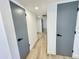 Hallway with neutral walls, wood-look tile flooring, and modern gray doors at 2213 E Janice Way, Phoenix, AZ 85022