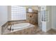 Luxurious bathroom featuring a soaking tub, tiled walls, and a glass block window at 3414 E Virgil Dr, Gilbert, AZ 85298