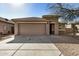 Tan colored house with a two-car garage and a gravel driveway at 5411 W Grenadine Rd, Laveen, AZ 85339