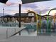 A community pool with a splash pad area and shade canopies overlooks a modern building at sunset at 3175 E Hayden Rose Ave, San Tan Valley, AZ 85143