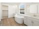 Bright bathroom featuring a soaking tub, double sink vanity, and wood-look flooring at 4922 W Hunter Trl, San Tan Valley, AZ 85144