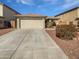 Tan single-story home featuring a well-manicured lawn and concrete driveway, showcasing suburban charm at 6556 S 258Th Dr, Buckeye, AZ 85326