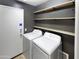 Practical laundry room with washer, dryer, shelving, and access door at 6556 S 258Th Dr, Buckeye, AZ 85326