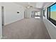 Expansive living room with large windows, neutral carpet, ceiling fan, and lots of natural light at 6556 S 258Th Dr, Buckeye, AZ 85326