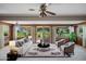 Bright living room featuring sliding doors to a pristine lawn, modern furniture, and a decorative ceiling fan at 10861 W Venturi Dr, Sun City, AZ 85351