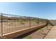 View of wrought iron fence, desert landscaping and neighboring homes under a clear blue sky at 5664 N 205Th Ln, Buckeye, AZ 85396