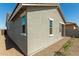 Side view of a beige stucco home with brown gravel landscaping and white trim at 5664 N 205Th Ln, Buckeye, AZ 85396