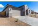 A garage and entryway are featured in the exterior view of a desert-landscaped modern home at 18440 W Monte Lindo Ln, Surprise, AZ 85387