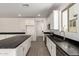 Bright kitchen features white cabinets, gray tile floor, stainless steel appliances, and large island at 18440 W Monte Lindo Ln, Surprise, AZ 85387