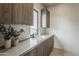 Stylish laundry sink with modern wood cabinetry and quartz countertop, bright window and greenery at 4414 N 29Th St, Phoenix, AZ 85016