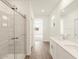 Hallway bathroom with a double sink vanity, wood-look tile flooring, and a glass-enclosed shower at 16001 W Cottontail Ln, Surprise, AZ 85387