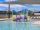 Community pool area featuring a colorful splash pad for , lounge chairs and shade canopies, and well-maintained landscaping at 16001 W Cottontail Ln, Surprise, AZ 85387