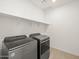 Modern laundry room with stainless steel washer and dryer, and overhead shelving at 16005 W Cottontail Ln, Surprise, AZ 85387