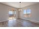 Bright dining room features wood-look tile floors, sliding glass door to patio, and a modern chandelier at 18955 W Ocotillo Rd, Waddell, AZ 85355