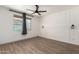 Bright bedroom with wood-look floors, modern ceiling fan, and ample natural light from a large window at 18428 W Robin Ln, Surprise, AZ 85387