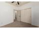 Bright bedroom featuring carpet, closet with doors, ceiling fan, and access to other rooms at 18428 W Robin Ln, Surprise, AZ 85387