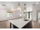 Open-concept kitchen boasts island with sink, modern pendant lighting and seamless flow into living area at 18428 W Robin Ln, Surprise, AZ 85387