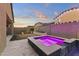 Backyard in evening with a stunning pool and spa illuminated with pink LED lighting at 18428 W Robin Ln, Surprise, AZ 85387