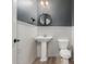 Stylish powder room showcasing wainscotting, pedestal sink, modern fixtures, and wood-look floor at 18428 W Robin Ln, Surprise, AZ 85387