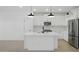 Modern kitchen with white cabinets, an island, stainless steel appliances, and sleek pendant lighting at 16610 N Dante Way, Maricopa, AZ 85138